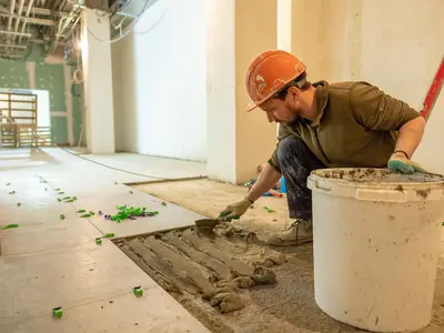 Tiler bedding floor tiles on adhesive